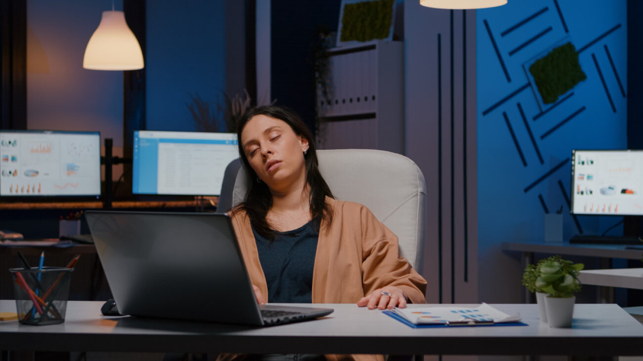 exhausted-entrepreneur-woman-sleeping-front-laptop-while-analysing-financial-statistics